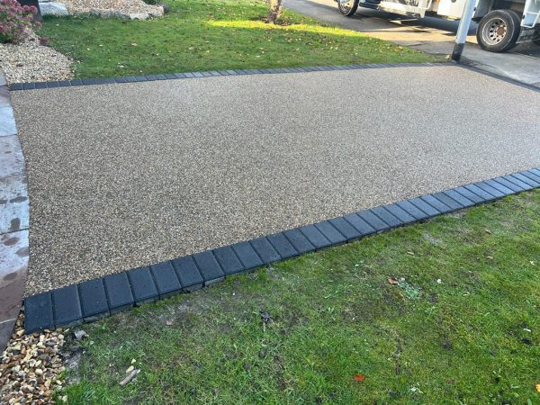 Gold resin driveway with paving border in Ardleigh